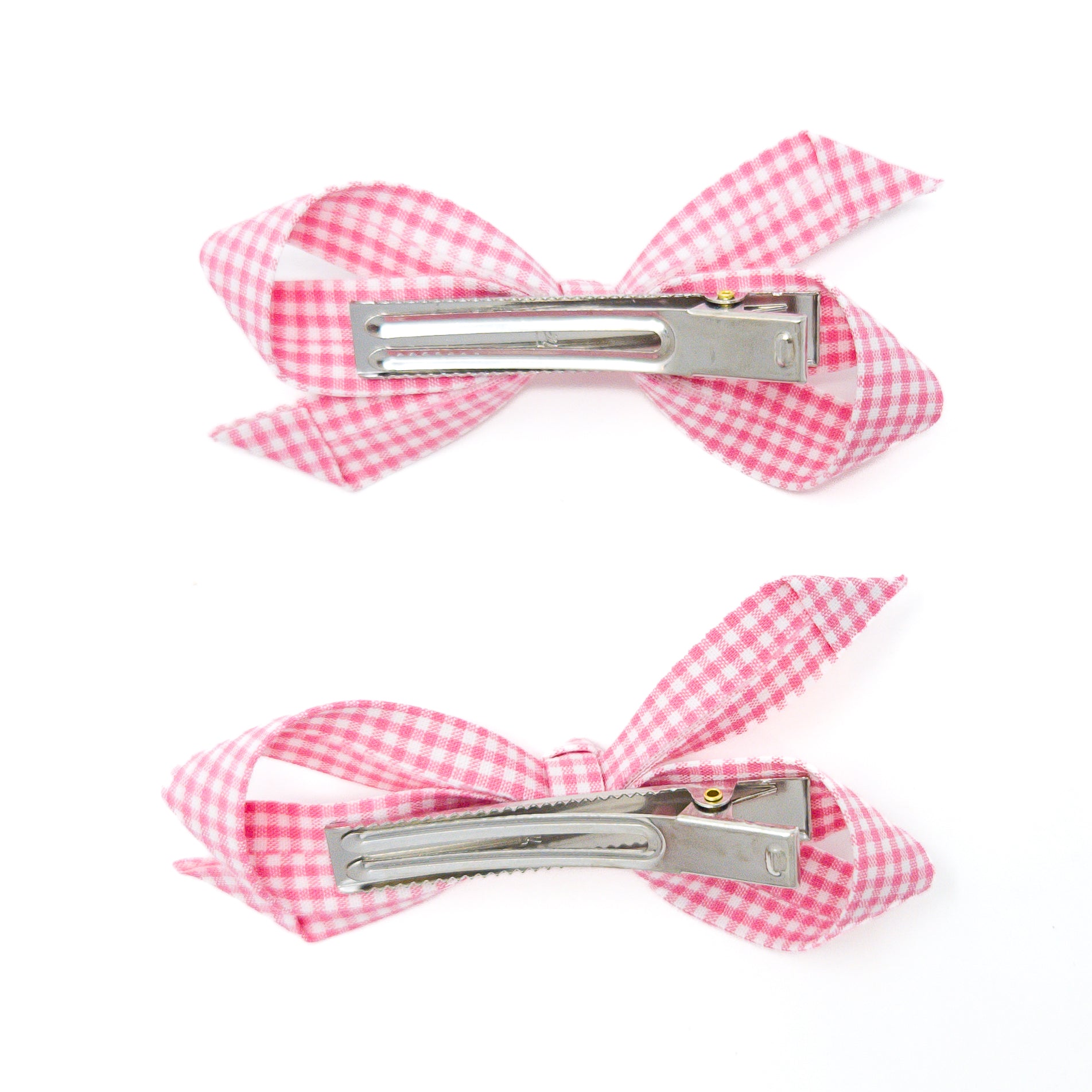 Two pink and white gingham hair clips, bow-shaped with silver alligator clips.