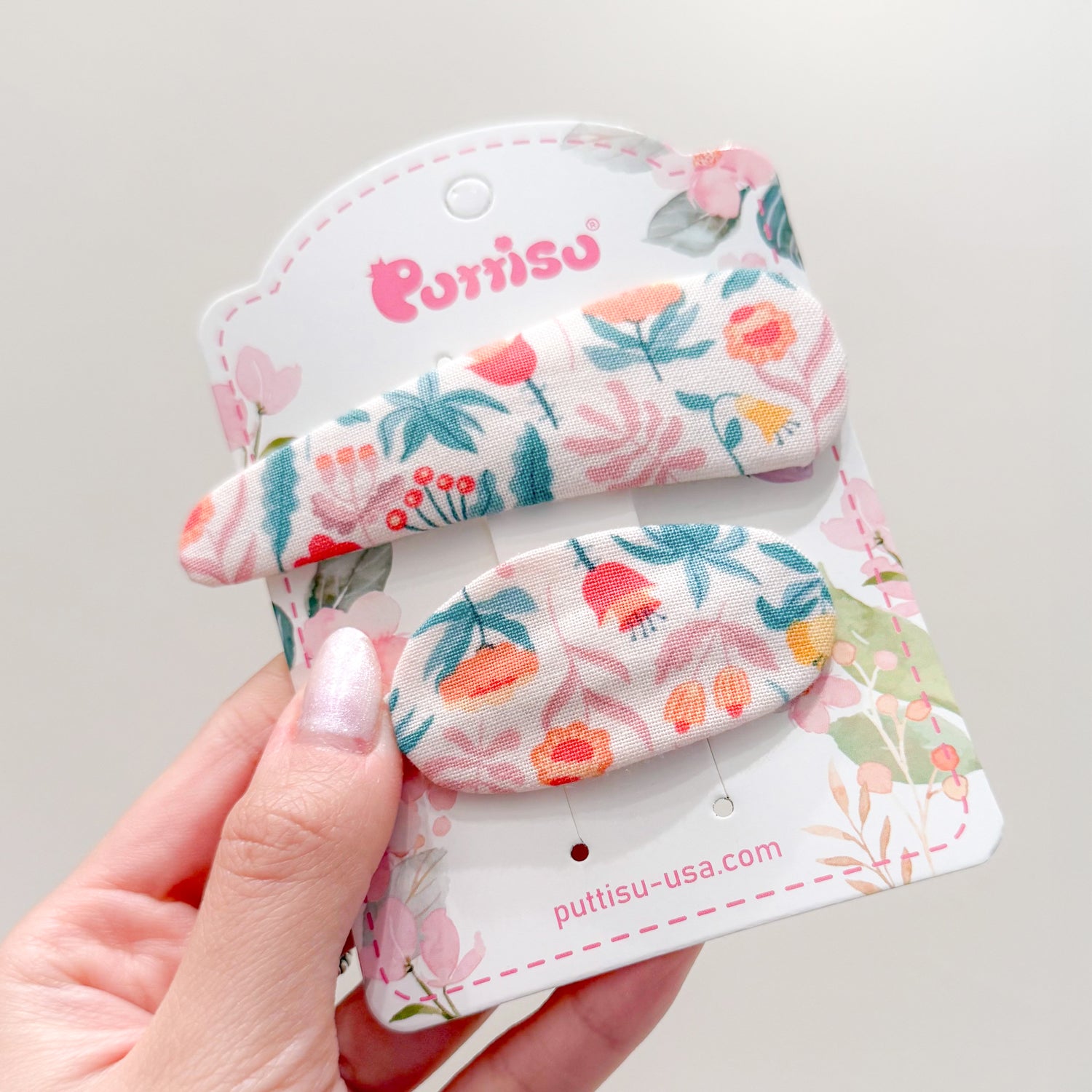 Two floral fabric hair clips on product packaging.