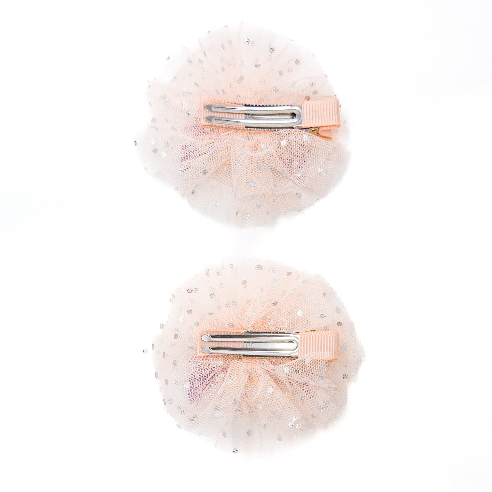 Two peach-colored, polka-dotted, tulle hair clips with silver metal closures.