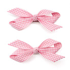 Two pink and white gingham bows with metal clips, arranged vertically on a white background.