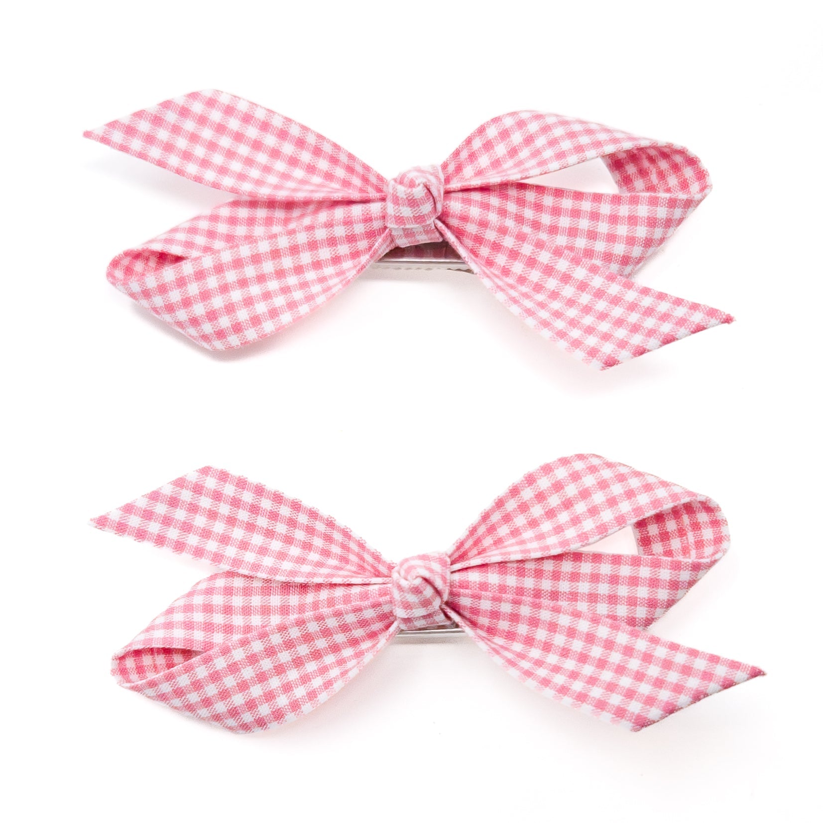 Two pink and white gingham bows with metal clips, arranged vertically on a white background.