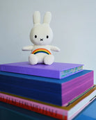 Stuffed bunny sitting on a stack of colorful books.