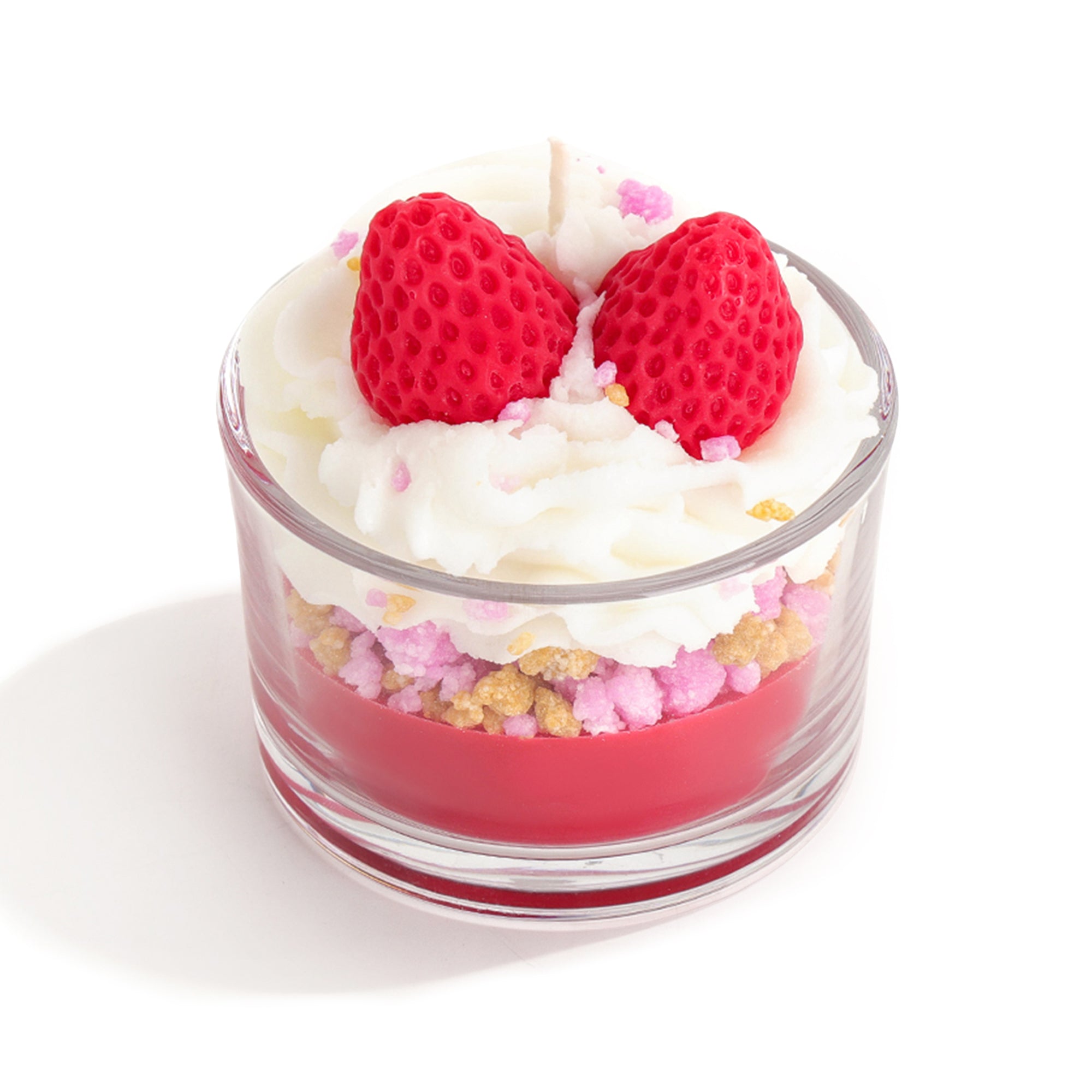 Small glass dessert with whipped cream, strawberries, and colorful candies on a white background