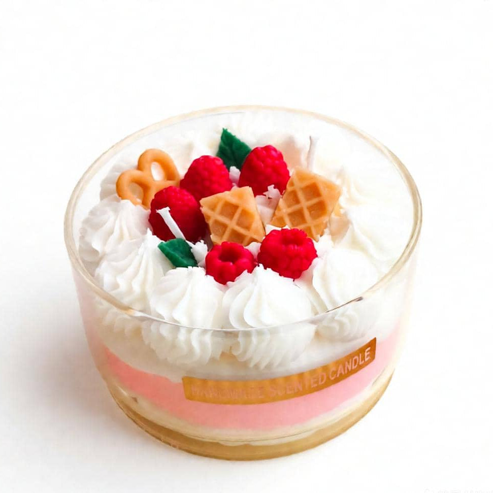 Decorative candle with whipped cream, raspberries, and waffle pieces on a white background