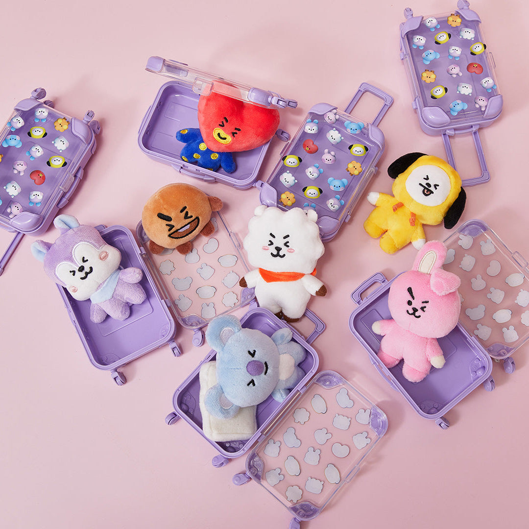 Assorted BT21 plush toys in miniature purple suitcases on pink background.