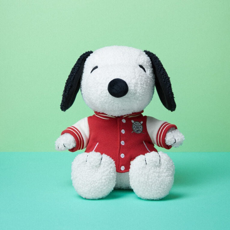 Stuffed Snoopy toy wearing a red and white jacket.