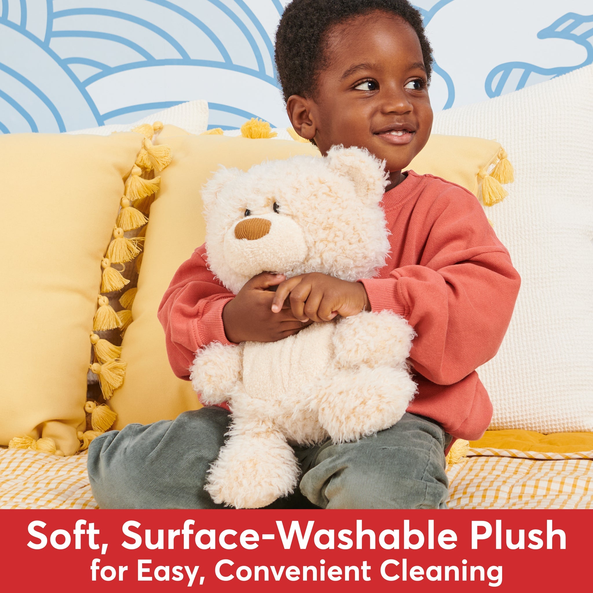 A young child in an orange shirt holding a teddy bear.