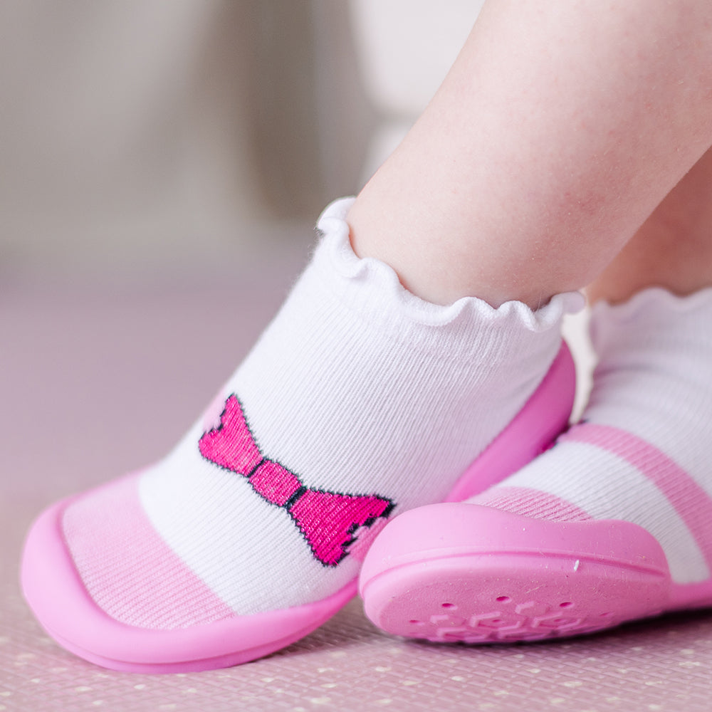 Baby socks with pink trim and bow detail.