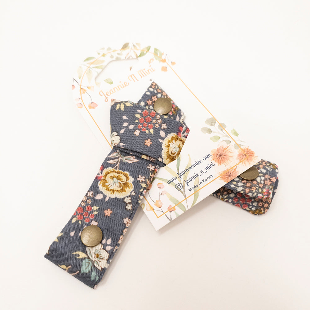 Floral-print fabric tie with metal snap closures on a white product card.