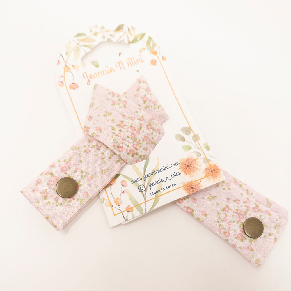 Pink floral bow hair tie with a bronze snap, displayed on a floral card.