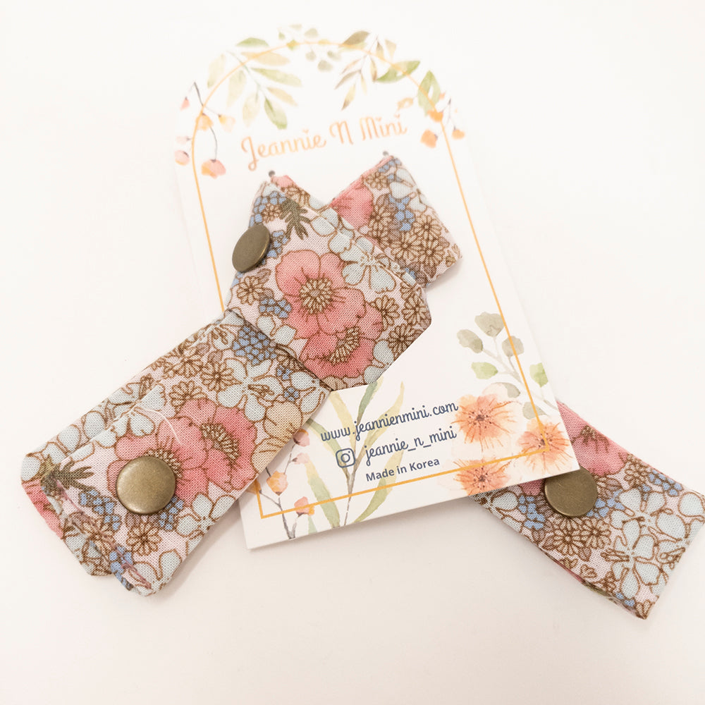 Floral fabric pacifier clips on a branded card.