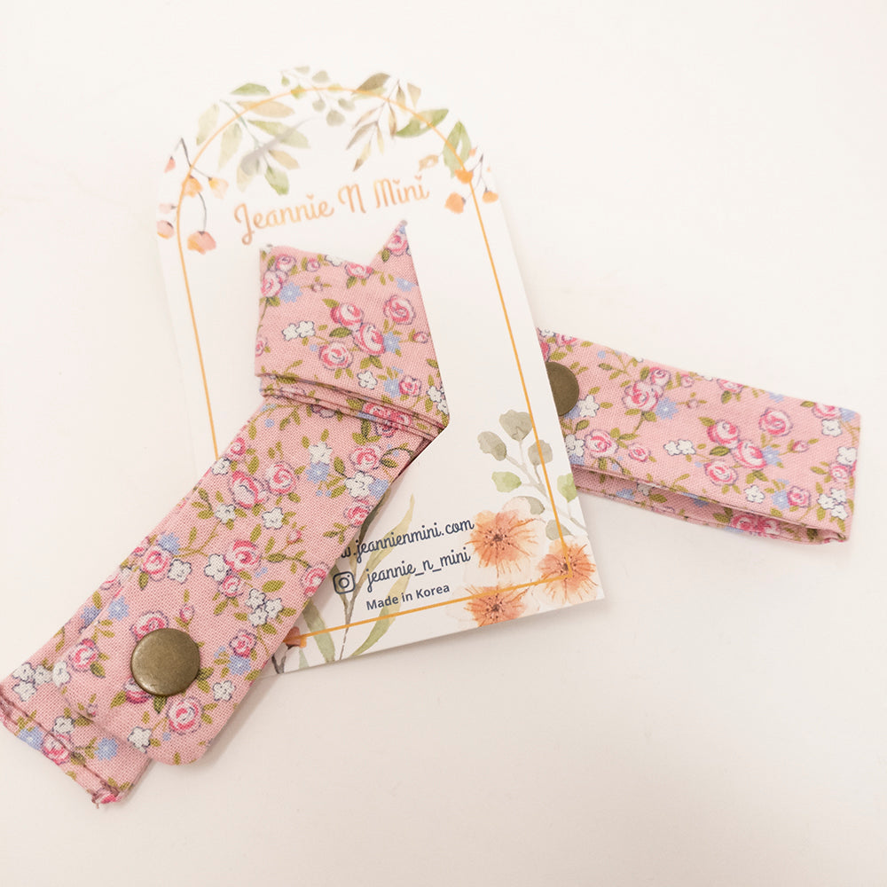 Pink floral fabric pacifier clips on a branded card.