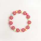 Close-up of a beaded bracelet featuring red and white striped beads, alternating with small, colorful pastel beads.