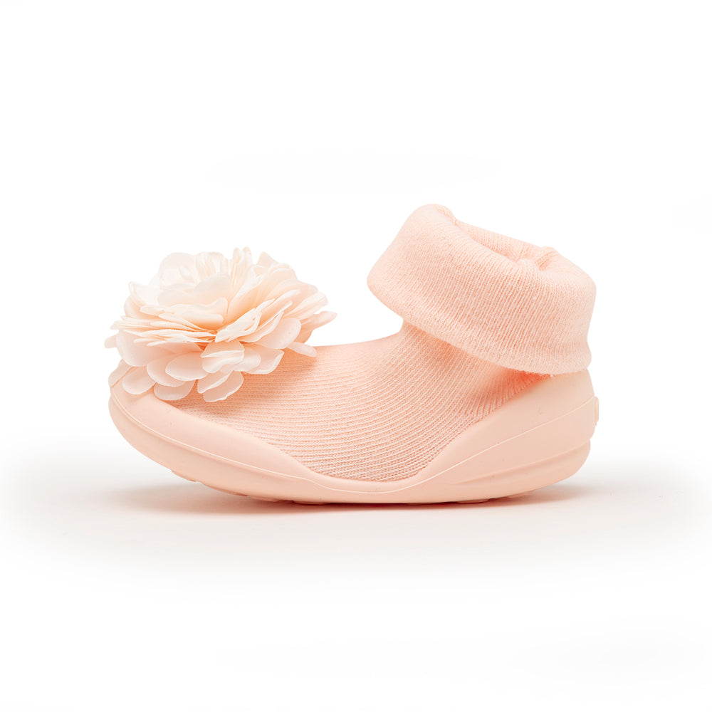 Peach-colored baby sock shoe with flower decoration.