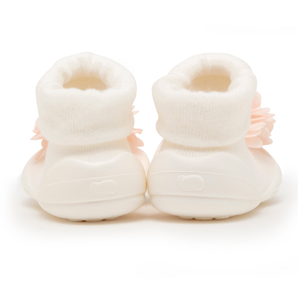 Two baby shoes, off-white, with a flower.