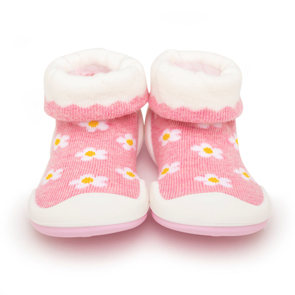 A pair of pink baby booties with a daisy pattern and white cuffs and soles.