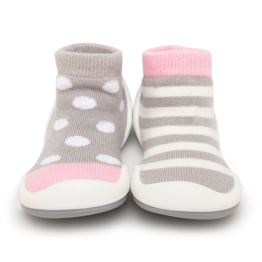 Pair of baby shoes, one with gray and white polka dots, the other with gray and white stripes.