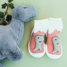 Pair of dinosaur-themed baby slipper socks with gray plush dinosaur toy.