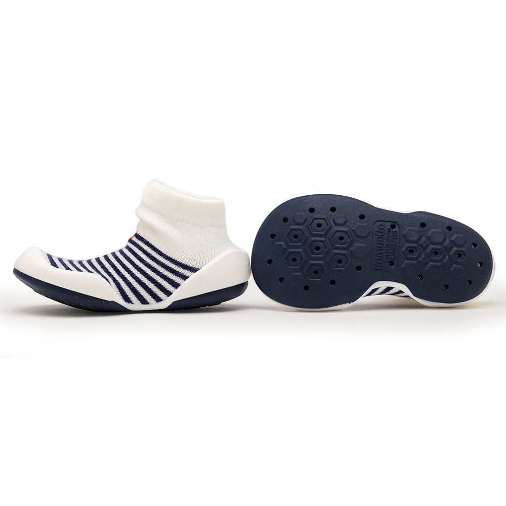 Two baby shoes, one white with navy stripes and one navy sole with hexagon tread.