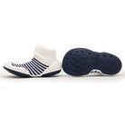 Two baby shoes, one white with navy stripes and one navy sole with hexagon tread.