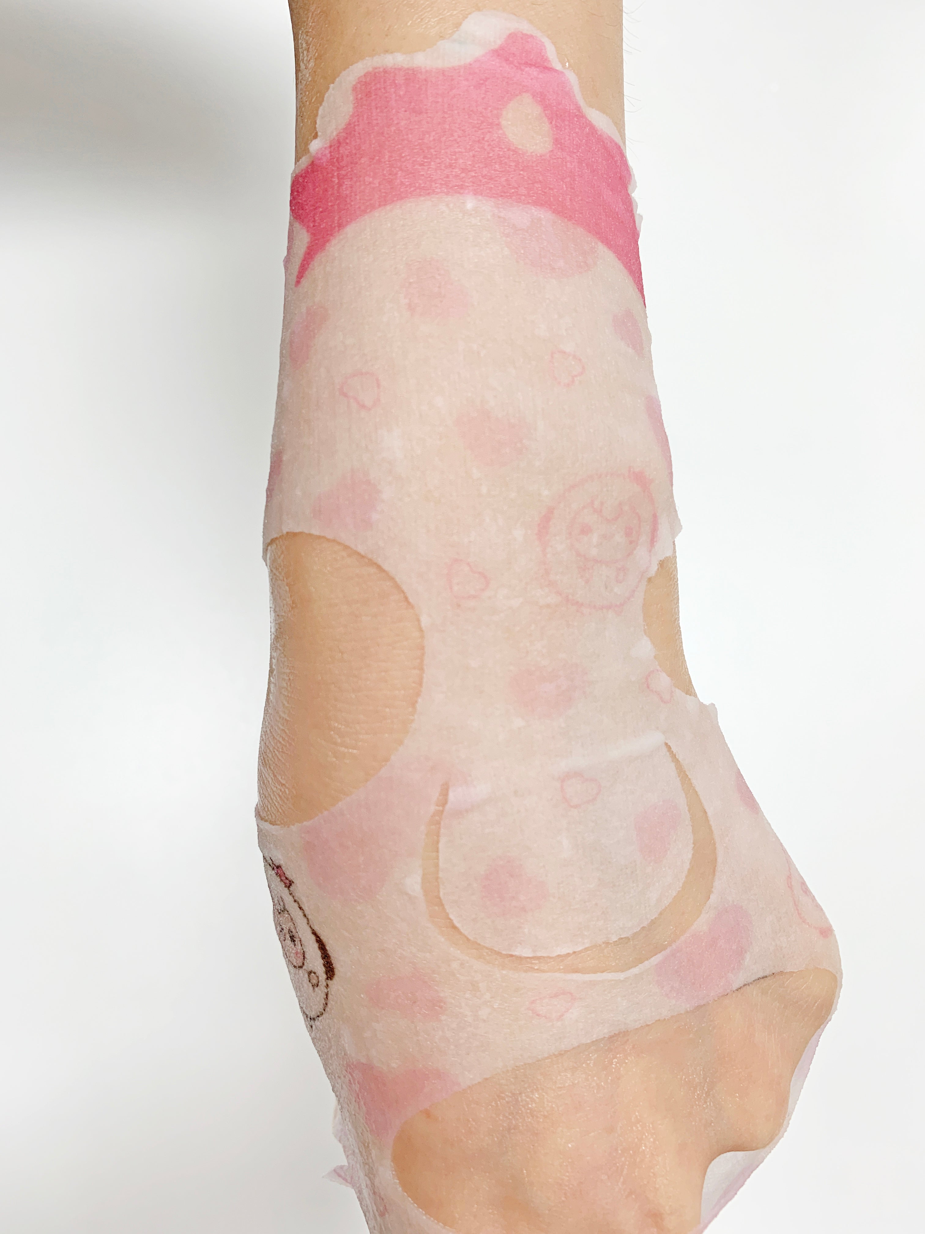 Arm with a pink and white patterned face mask.