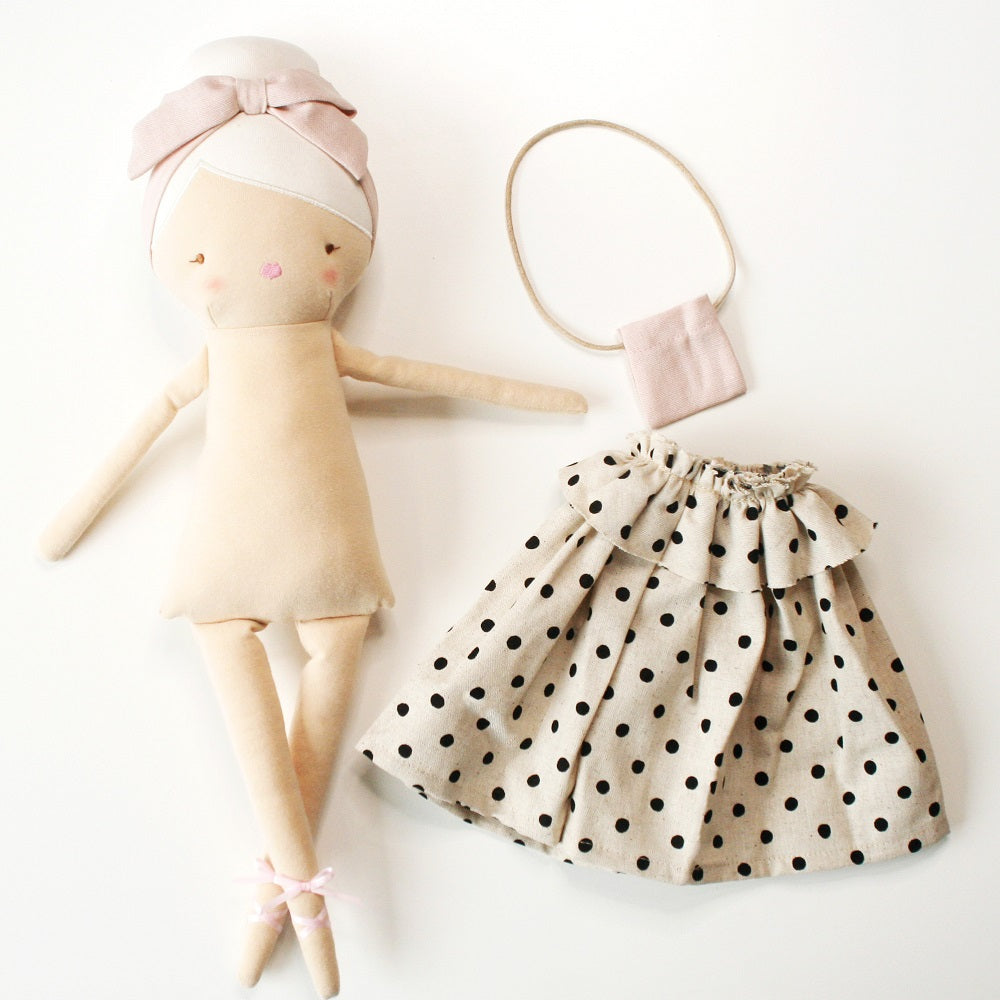 A cloth doll and doll clothes, including a polka dot skirt and handbag.