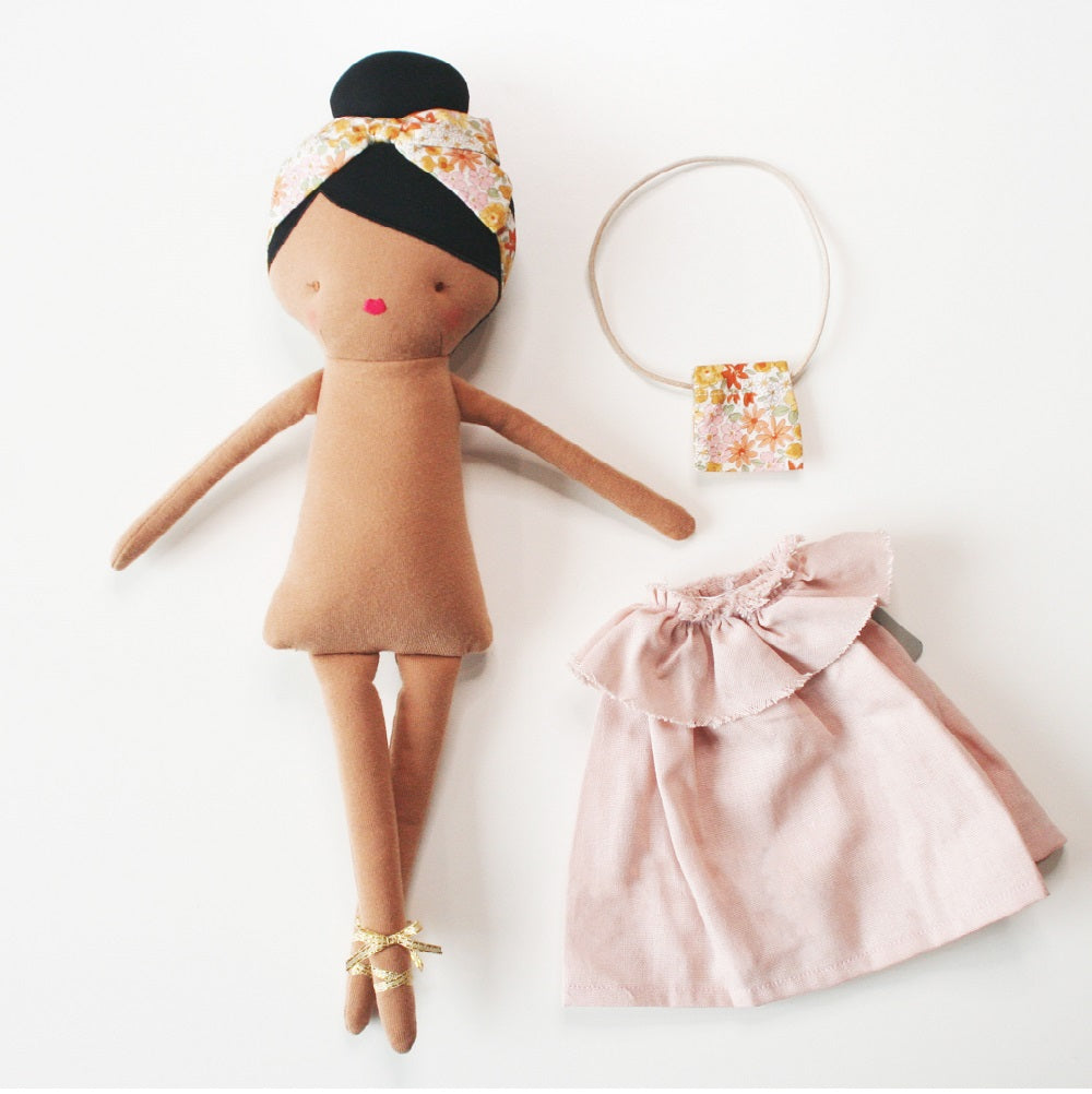 Cloth doll with pink dress and floral jewelry.
