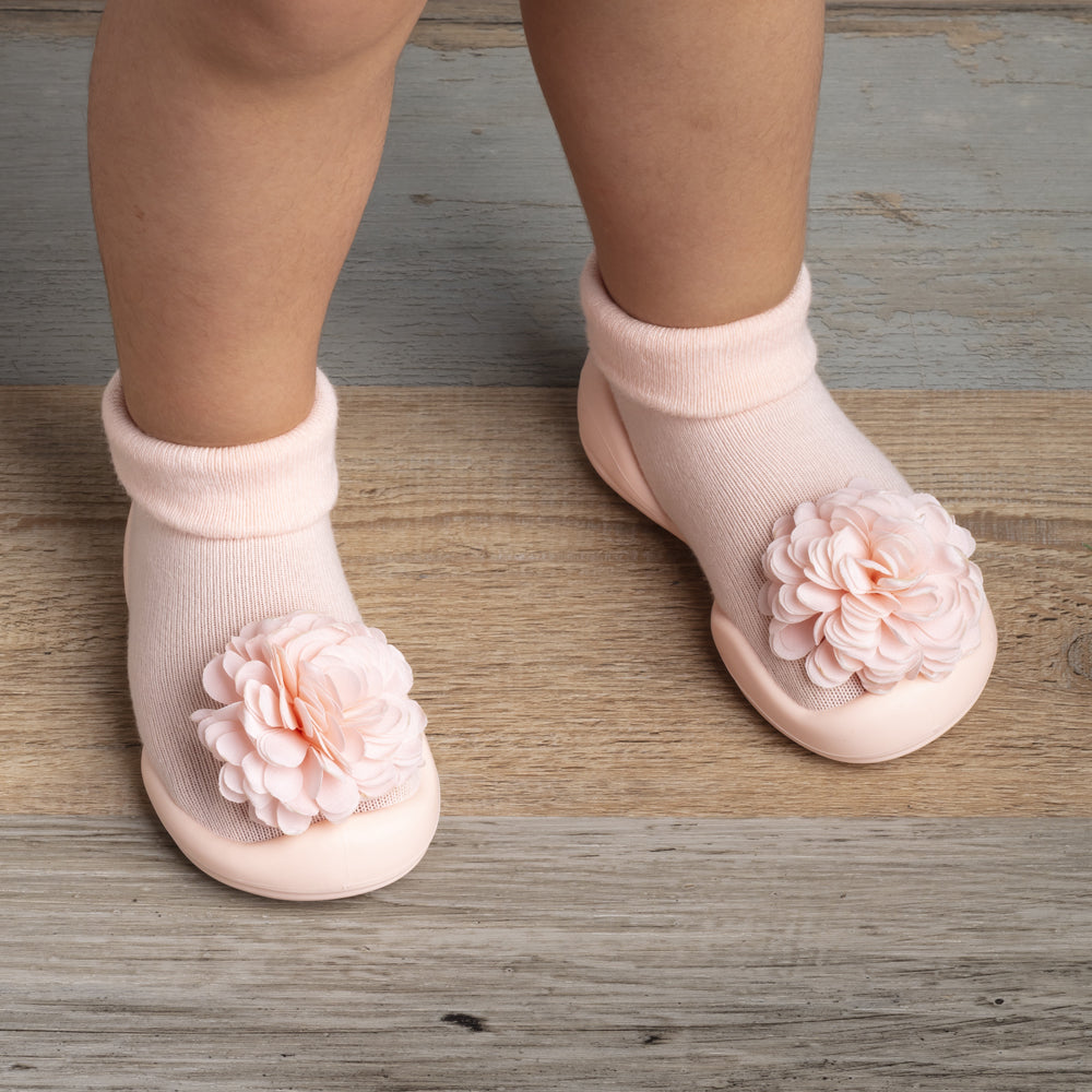Baby wearing pink flower-decorated slipper socks.