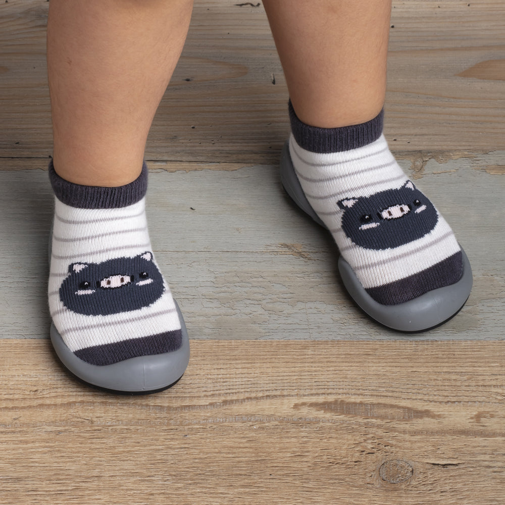 Child's feet in striped sock shoes with bear design.