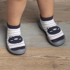 Child's feet in striped sock shoes with bear design.
