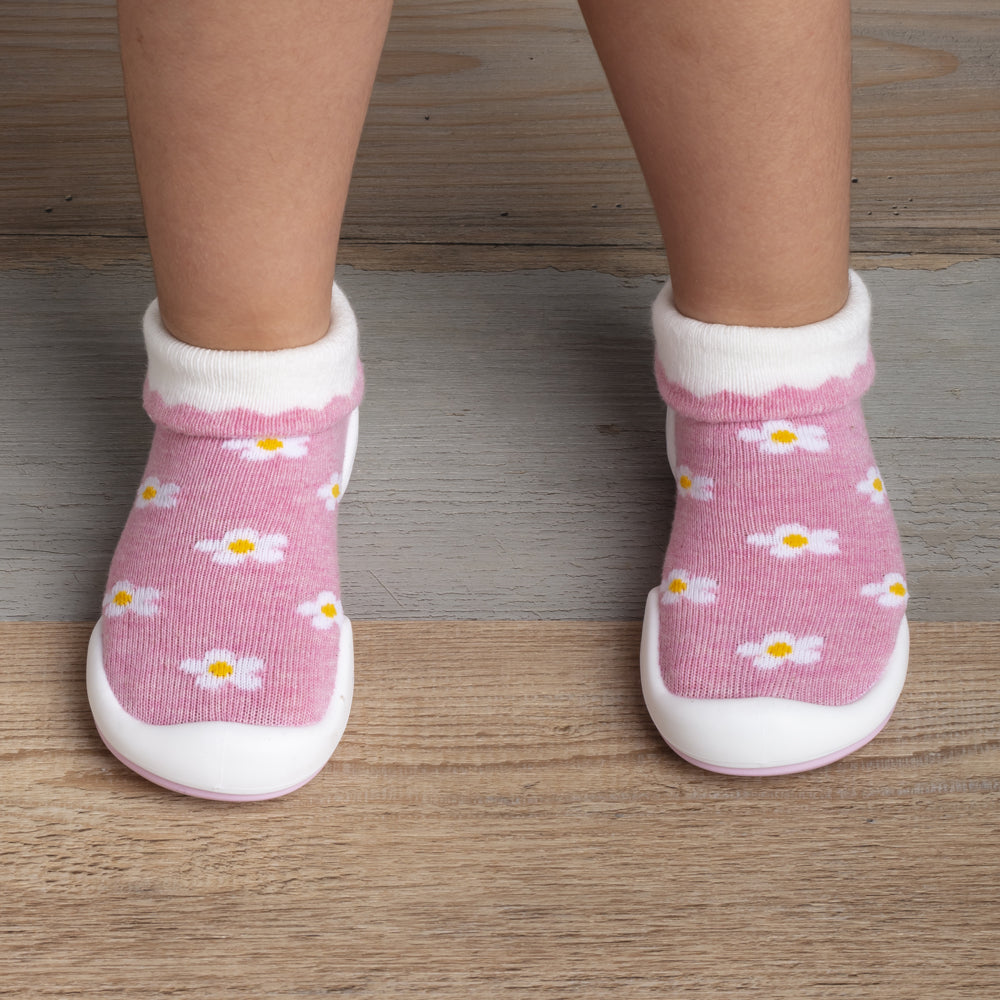 A pair of baby's pink sock-shoes with white daisy print.