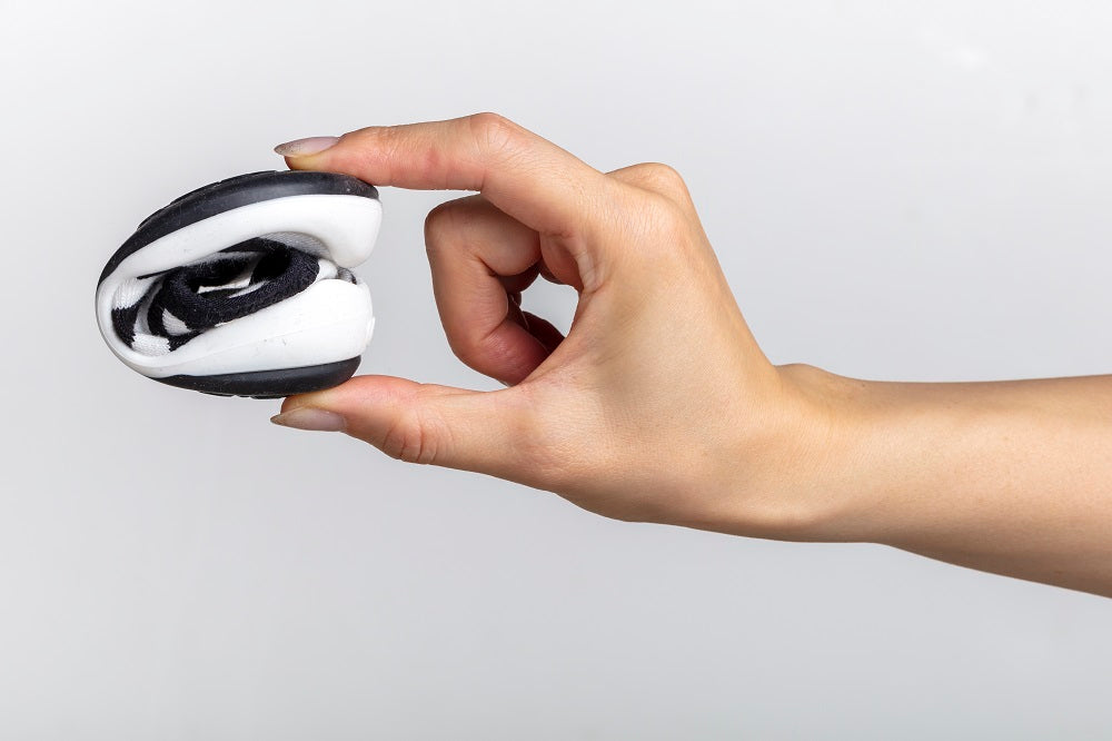 Hand holding folded black and white shoe.