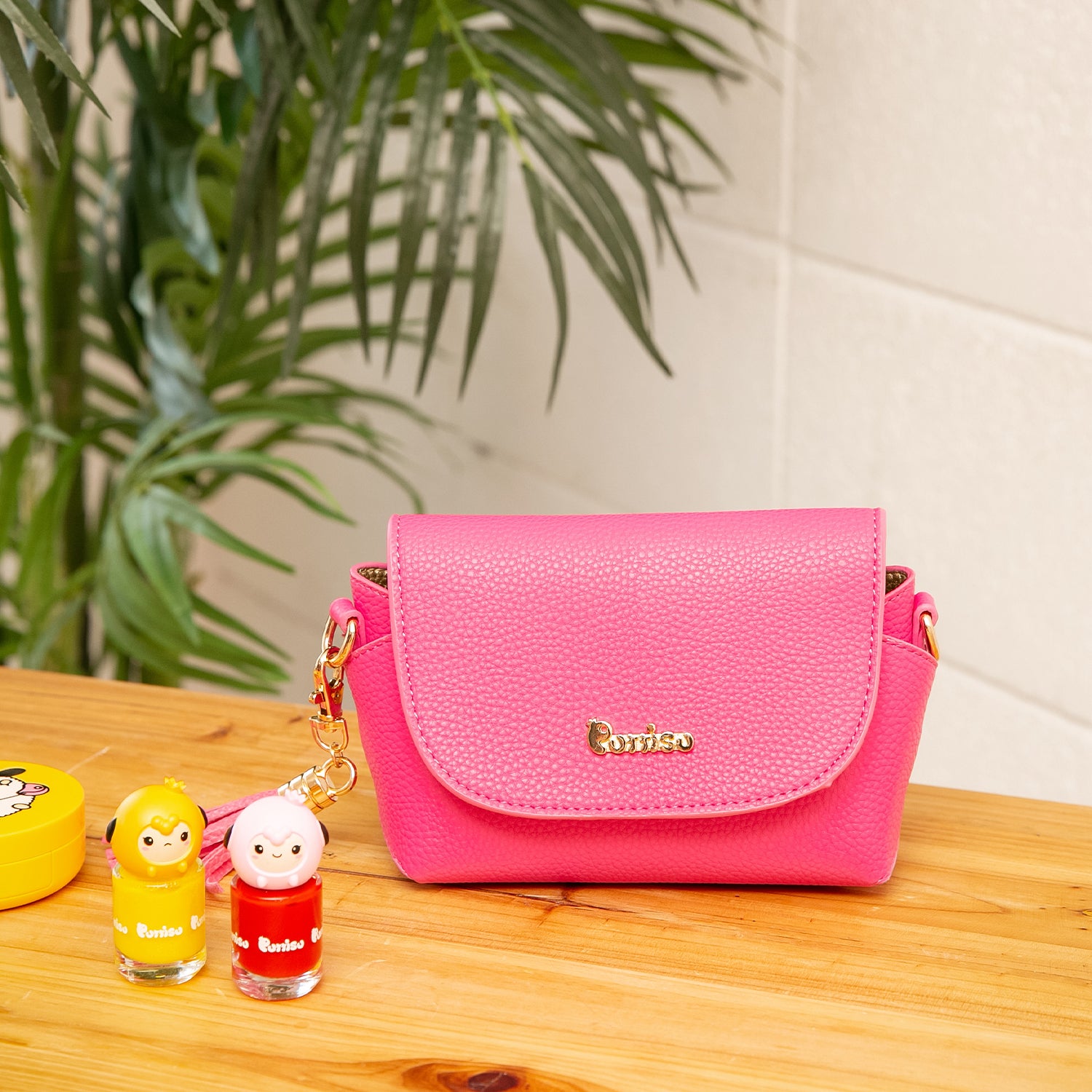 Pink faux-leather purse with nail polish bottles on wood table.