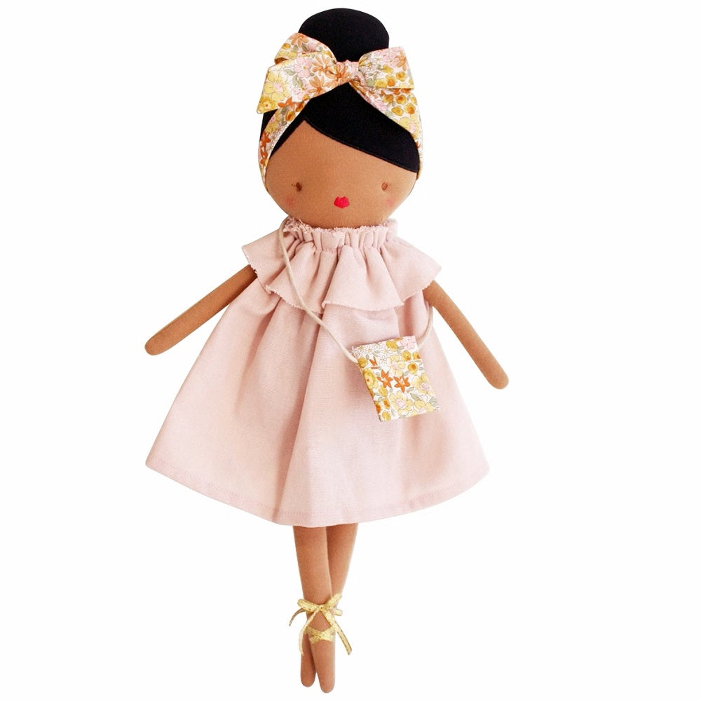 Stuffed doll with dark skin wearing a pink dress, floral headband, and gold ballet shoes.