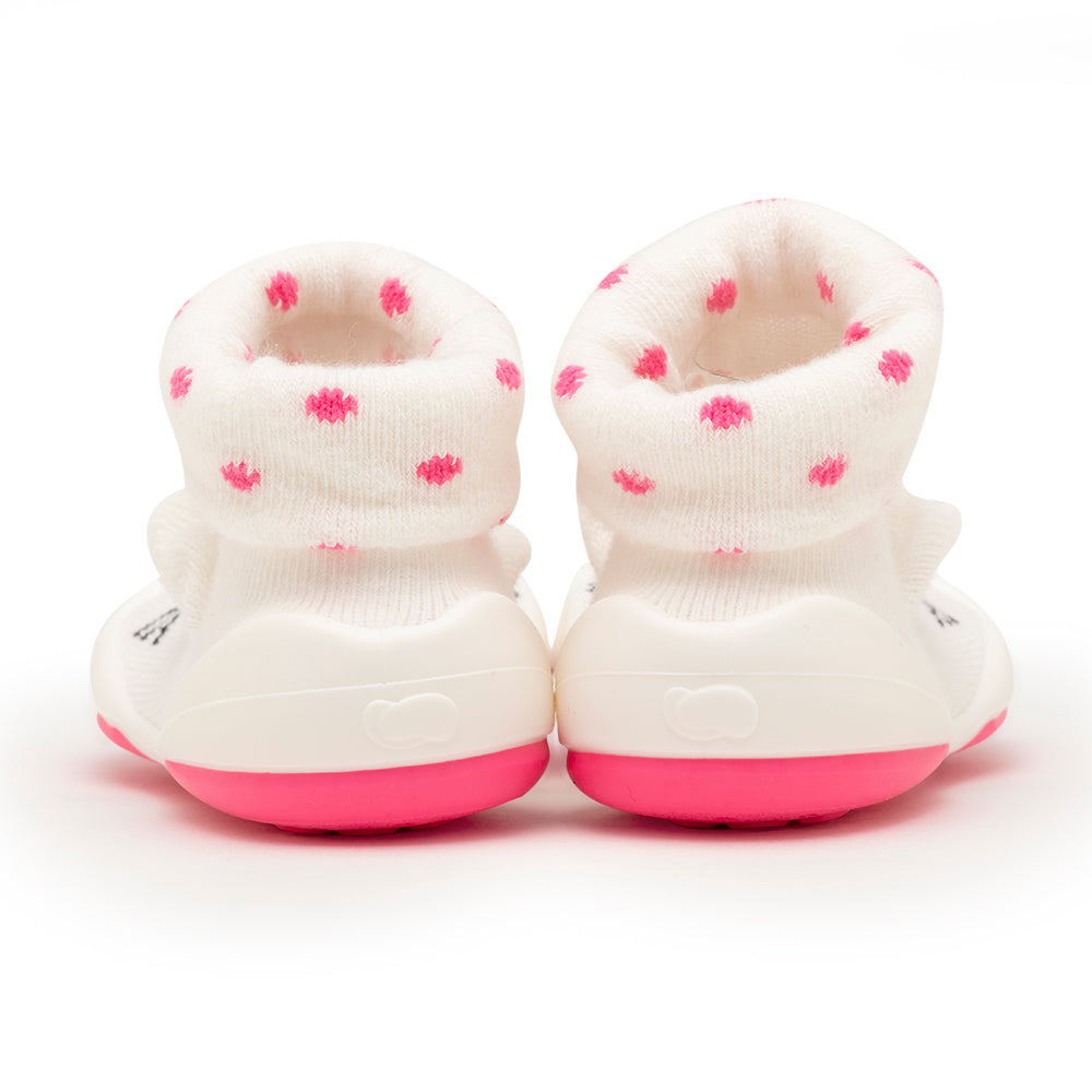 Two white baby booties with pink polka dots.