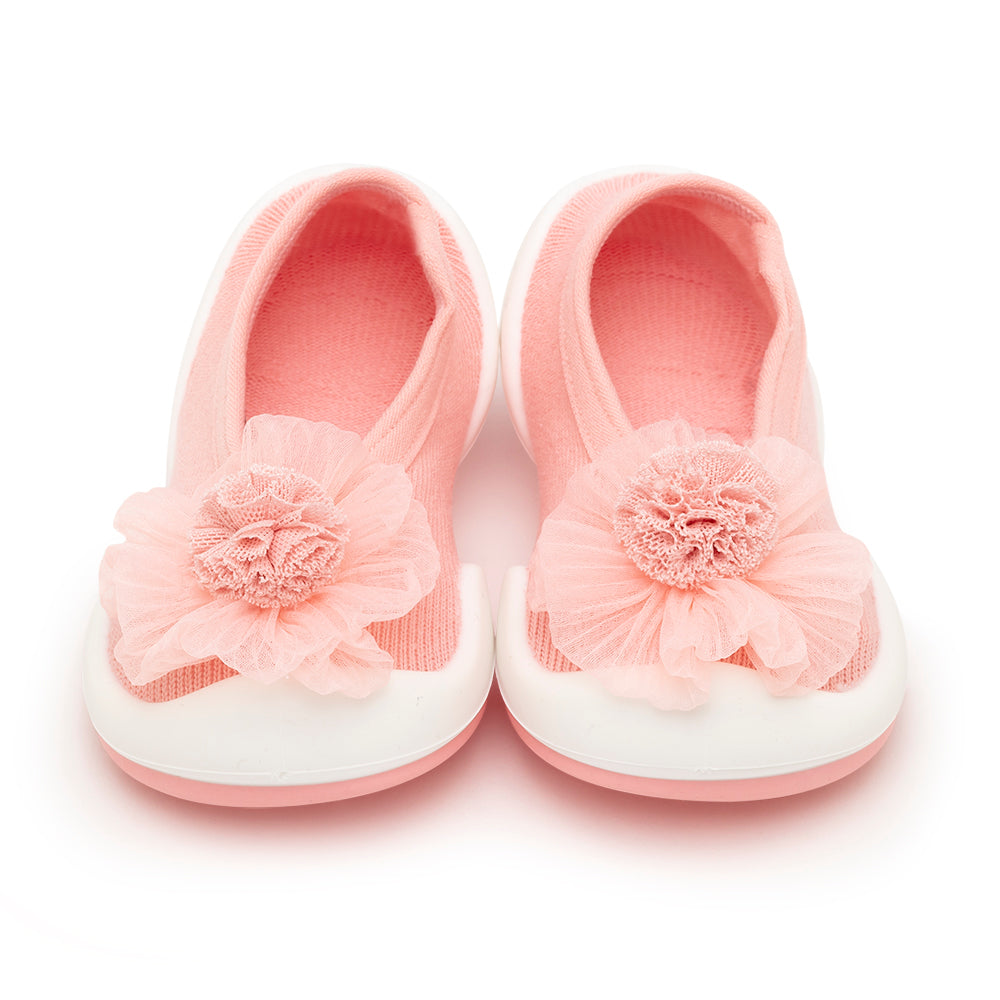 Pair of pink baby shoes with white soles and fabric flowers.