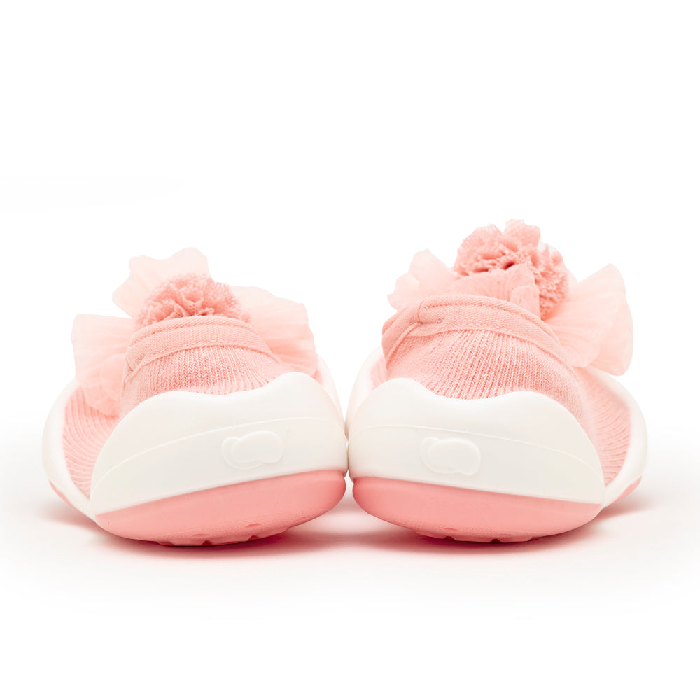 Rear view of pink baby shoes with pom poms and white soles.