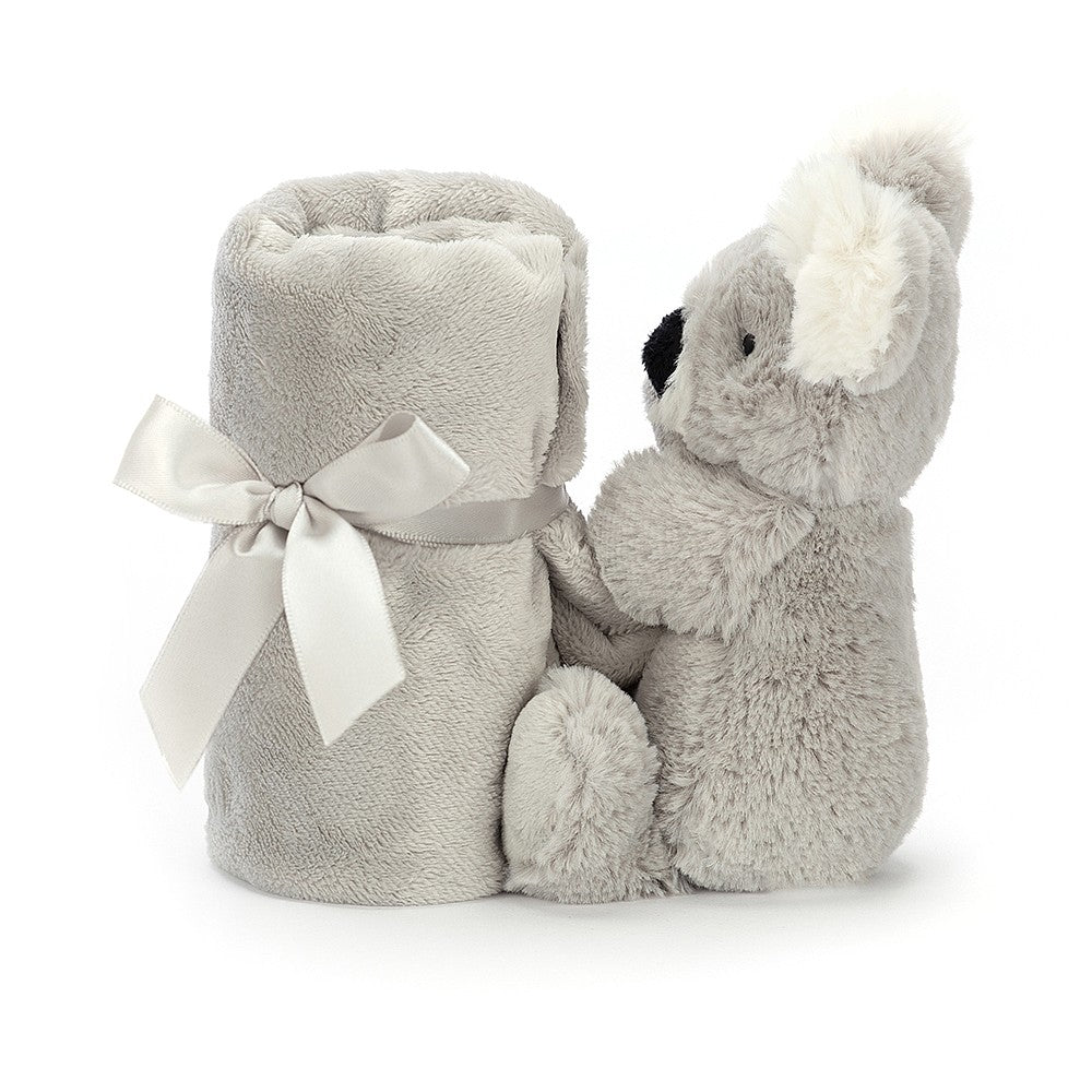 Gray koala plush toy sitting next to a rolled-up gray blanket tied with a white satin ribbon.