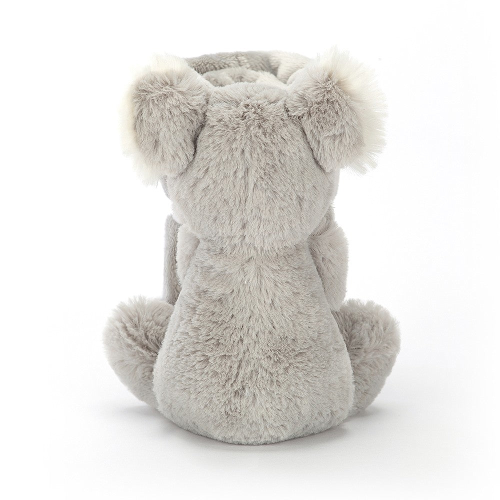 Rear view of a grey, plush koala toy sitting.