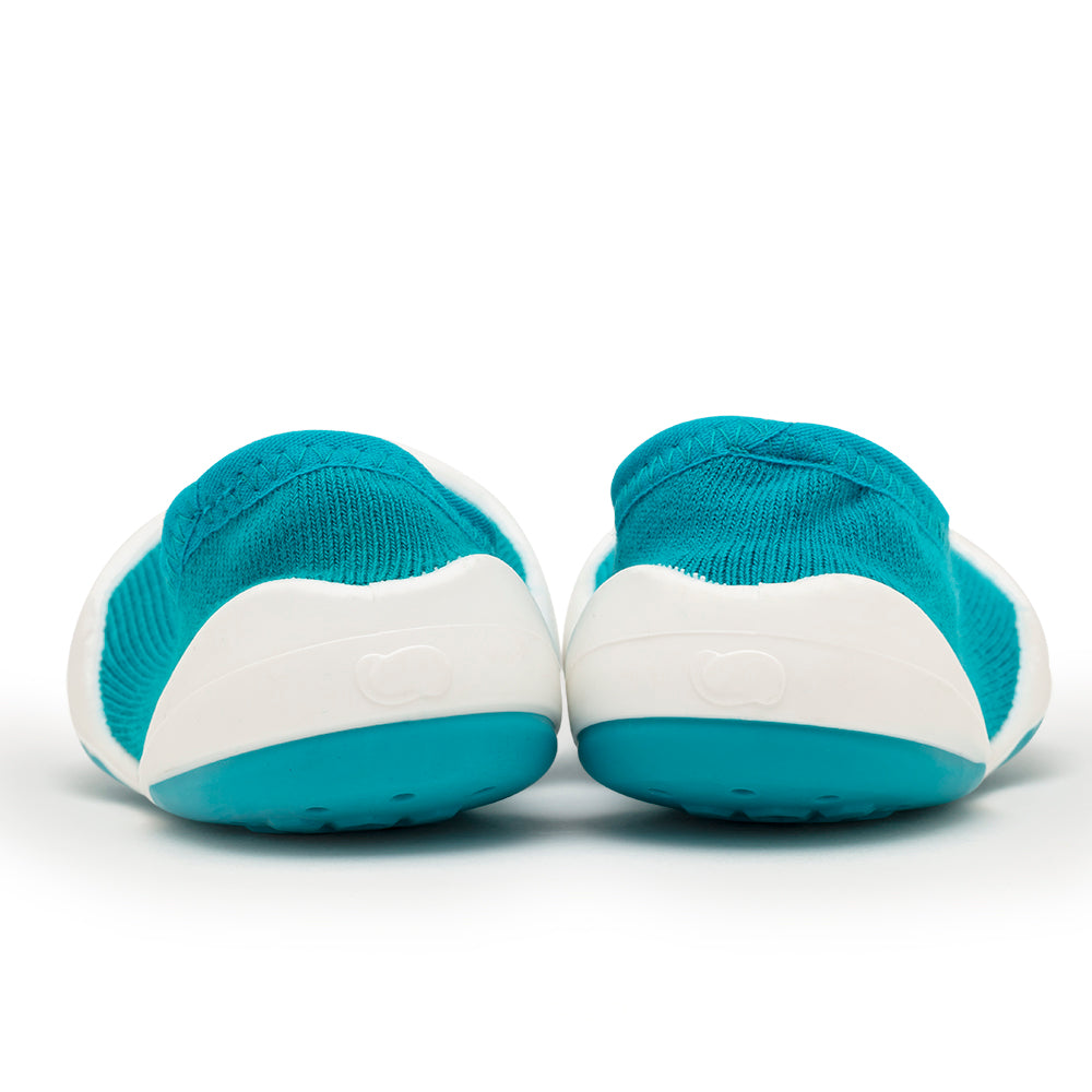 A pair of turquoise and white shoes seen from behind.