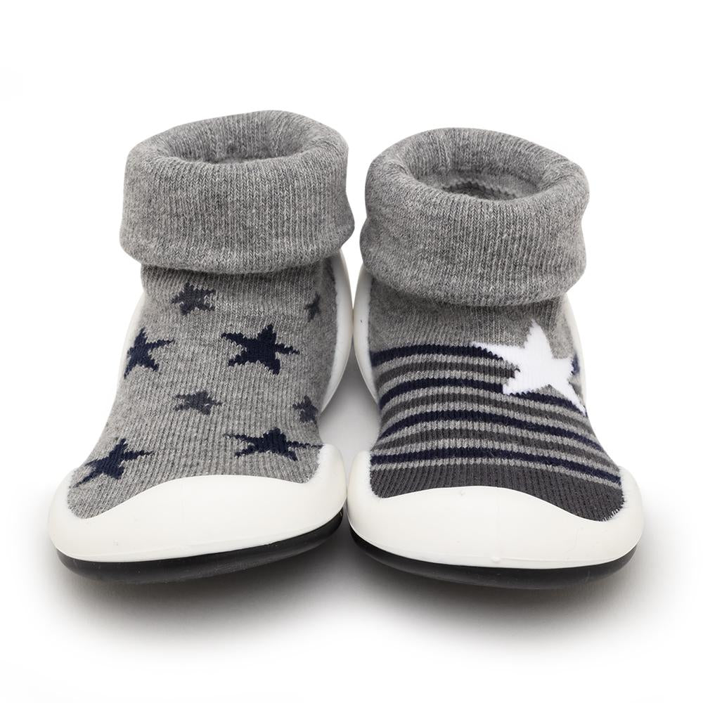 A pair of grey sock-shoes for babies or toddlers, with star patterns and white soles.