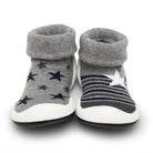 A pair of grey sock-shoes for babies or toddlers, with star patterns and white soles.