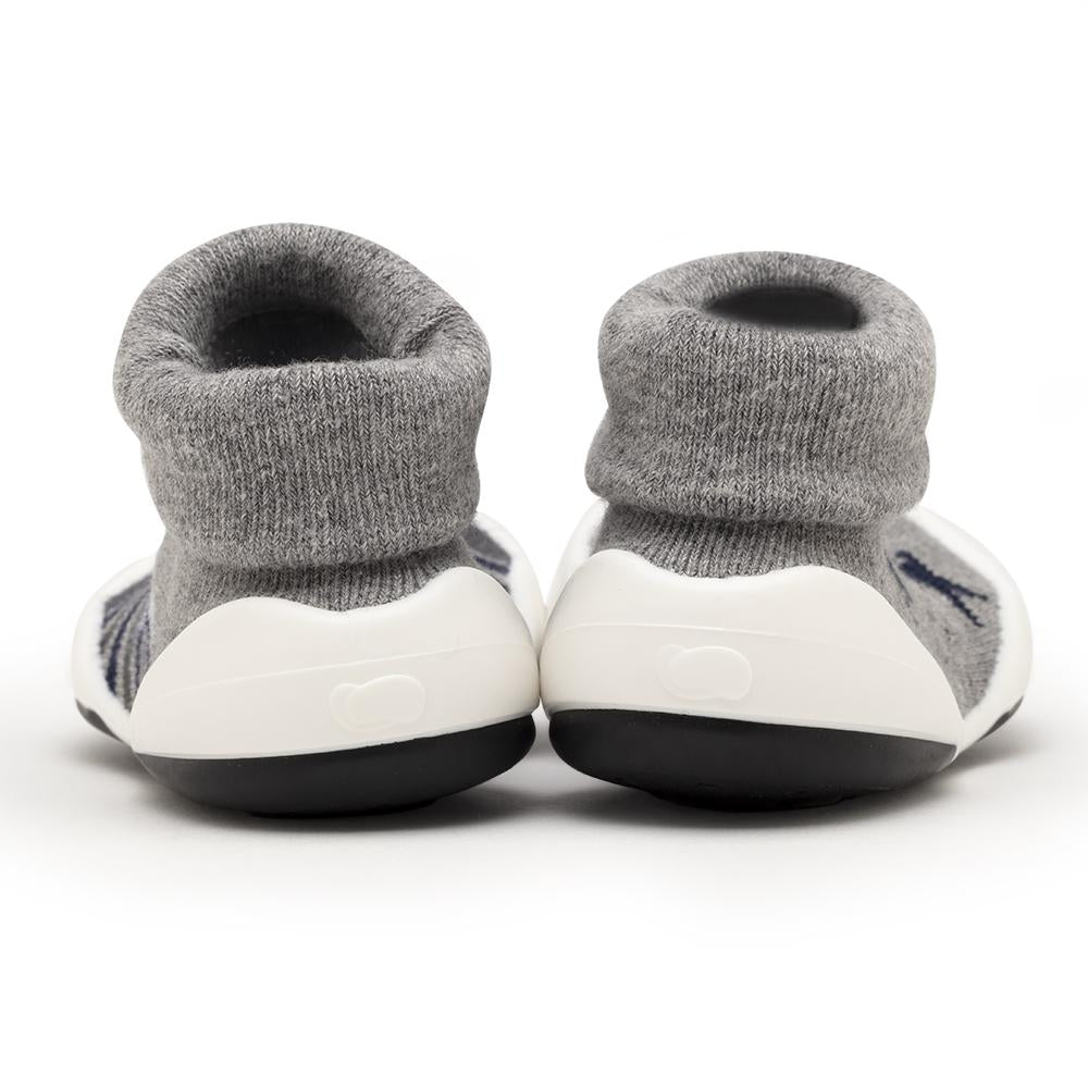 Two baby shoes with gray sock tops and white and black soles.