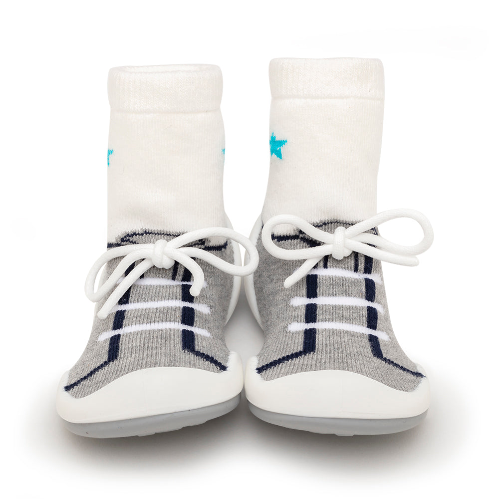 A pair of baby shoe socks, white with a gray sneaker pattern.