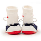 Two baby sock shoes, viewed from behind.  The socks are white with red stars and have blue and white stripes.  The soles of the shoes are red and the heel is white.