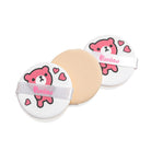 Three round makeup puffs, two white with pink cartoon bears and one tan.