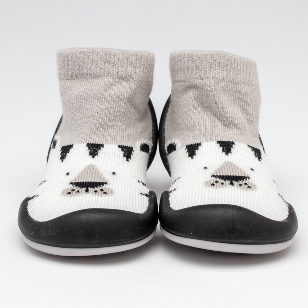 Pair of baby sock shoes with black rubber soles, gray socks, and a white foot area with a bear face design.