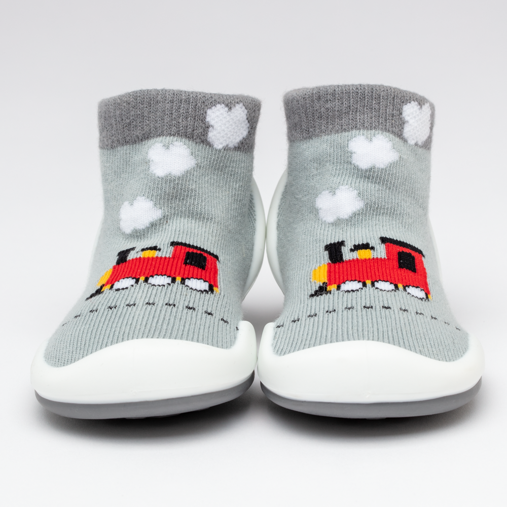 Close-up of two gray sock shoes with red train designs and white clouds.