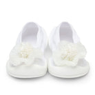 Pair of white baby shoes with flower embellishments.