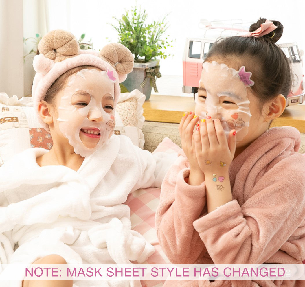 Two young children in robes and facial masks, seated with pillows, and decorative objects in the background.